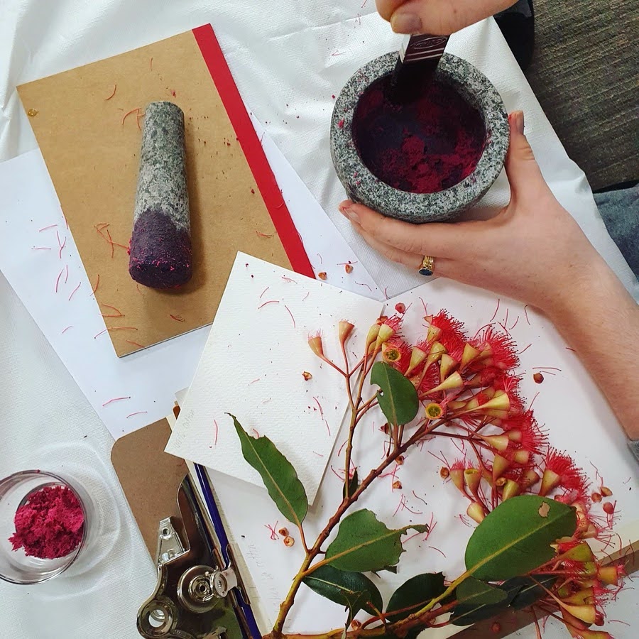 Natural pigments being ground beside leaves and flowers